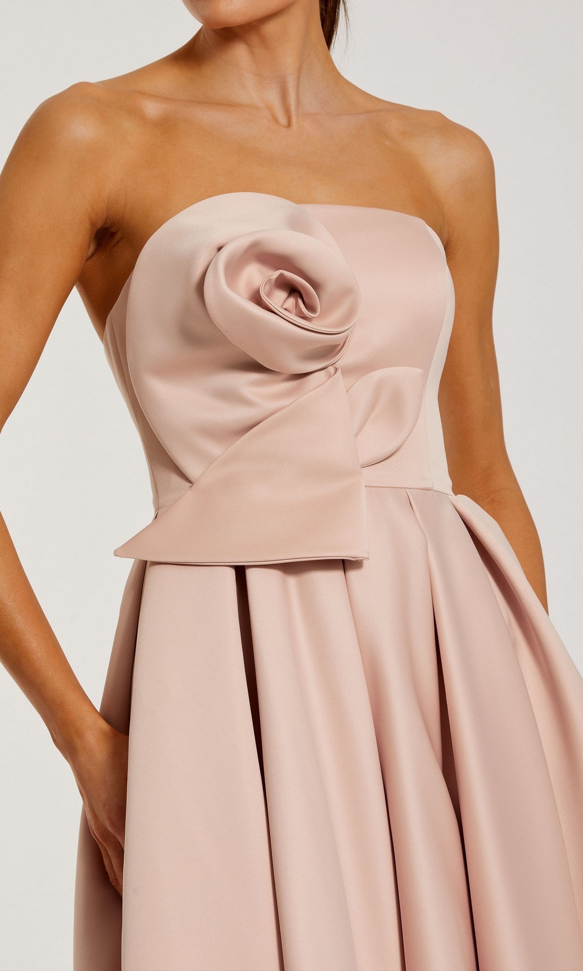 Woman wearing the Emerald Tea-Length Formal Dress (Mac Duggal 2330), featuring pleats and a large fabric rose detail on the bodice.